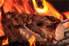 Carne asándose sobre las llamas de la brasa de leña