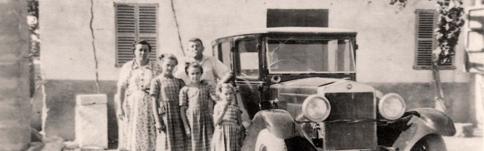 La familia junto a un coche antiguo delante de la casa